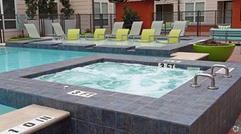 a jacuzzi pool with yellow lounge chairs and a swimming pool